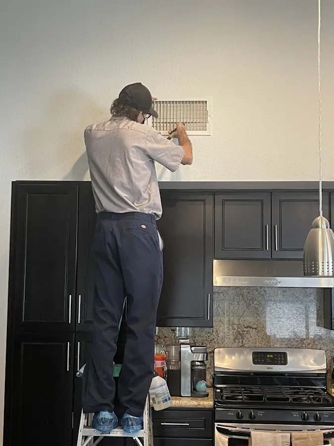 Technician inspecting an air vent during HVAC service in Lucas